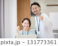 緑のある窓際でカメラ目線の名札を付けた笑顔の男女のパソコンを持つ爽やかなオフィスカジュアルミドル 131773361