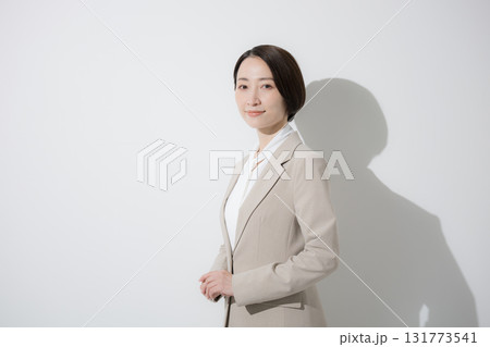 ベージュのスーツを着た営業など、美人な女性のビジネス上半身　立つのカメラ目線　白背景真剣な表情 131773541