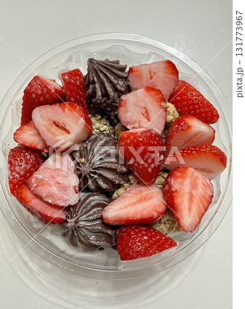 Swirled yogurt ice cream dessert served in a cup, smooth creamy texture with glossy surface, topped with fresh fruit pieces, highlighting its refreshing and inviting appearance in detail 131773967