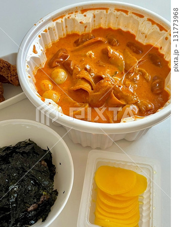 Chewy rose yeotteok coated in spicy pink sauce paired with a crispy corndog, blending sweet, savory, and spicy flavors. A trendy Korean street food duo perfect for food promotions. 131773968