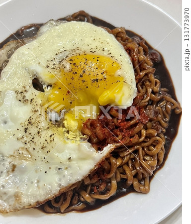 Savory jjapagetti noodles with a rich black bean sauce, topped with green onions and sesame seeds. A comforting Korean favorite that combines depth and flavor in each bite. 131773970