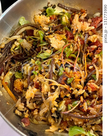 Bibimbap, a vibrant Korean rice dish topped with a variety of seasoned vegetables, gochujang, and a fried egg, often accompanied by sliced meat. Mixed together, it creates a flavorful and balanced. 131773990