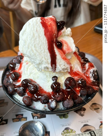 Refreshing bingsu, a Korean shaved ice dessert topped with sweet ingredients like red beans, fruits, and condensed milk. A perfect treat to cool down on hot days. 131774887