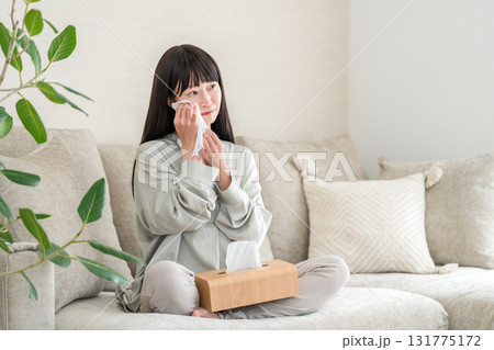 ソファーでテレビや映画を見て涙を拭く若いアジア人女性 131775172