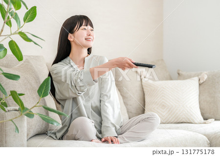 リビングのソファーに座りテレビ鑑賞する若いアジア人女性 リビングのソファーに座りテレビ鑑賞する若いアジア人女性 131775178