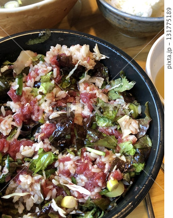 Yukhoe bibimbap with fresh veggies, rice, seasoned raw beef, raw egg yolk, and gochujang. offering a bold mix of flavors and textures in a classic Korean dish. 131775189