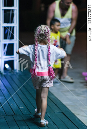 A girl with pink hair and pink shorts is standing on a stage A girl with pink hair and pink shorts is standing on a stage 131775252