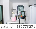 A pink cake is being photographed by a cell phone 131775271