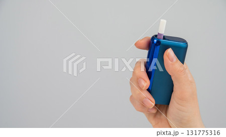Woman holding electronic cigarette on white background. Tobacco heating systems. 131775316