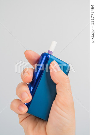 Woman holding electronic cigarette on white background. Tobacco heating systems. Woman holding electronic cigarette on white background. Tobacco heating systems. 131775464