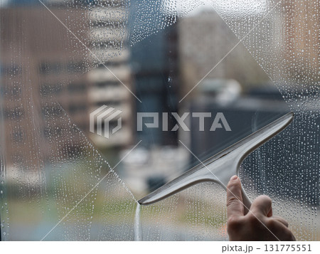 A woman washes a window with a special scraper. A woman washes a window with a special scraper. 131775551