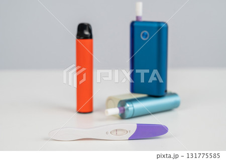 Pregnancy test and electronic cigarette and disposable vape on white table. Pregnancy test and electronic cigarette and disposable vape on white table. 131775585