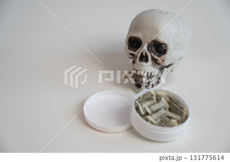 Skull Chewing Tobacco on a White Table. 131775614