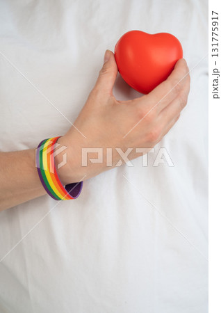 Caucasian woman with rainbow bracelet holding heart.  131775917