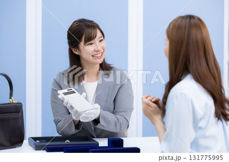 買取業者 窓口で査定をしている女性 買取業者 窓口で査定をしている女性 131775995