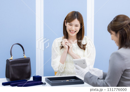 買取業者　バックと貴金属の査定を受ける女性 131776000