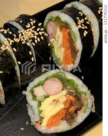 Delicious kimbap rolls filled with fresh vegetables, seasoned rice, and savory proteins, all wrapped in crisp seaweed. A perfect combination of flavor and texture in every bite. 131776312