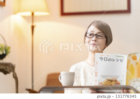 リビングで料理のレシピ本を見るシニア女性 131776345