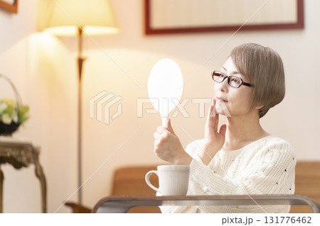 リビングで手鏡を見るシニア女性 131776462