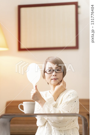 リビングで手鏡を見るシニア女性 131776484