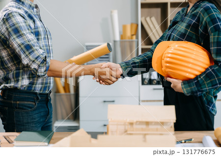 Construction team shake hands greeting start new project plan behind yellow helmet on desk in office center to consults about their building project. 131776675
