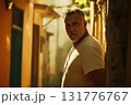 Middle aged man in shadowed alley with dramatic sunlight highlighting intense expression 131776767