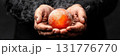 Hands cradle glowing orb surrounded by mist on black background 131776770