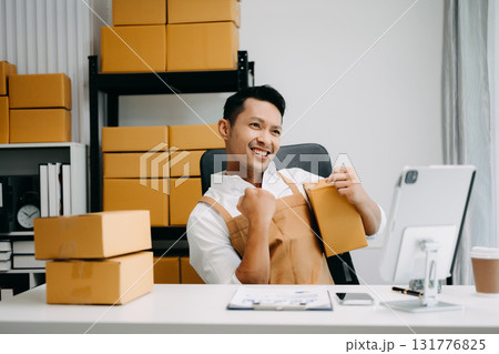 Startup small business SME, Entrepreneur owner man using smartphone or tablet taking receive and checking online purchase shopping order to preparing pack product box. in office 131776825