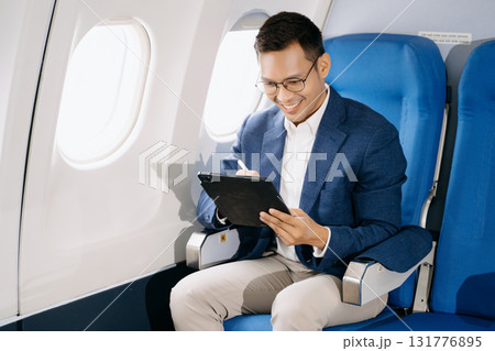 Asian executive excels in first class, multitasking with digital tablet, laptop and smartphone. Travel in style 131776895