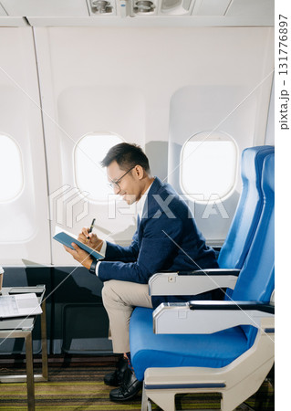 Young Asian executive excels in first class, multitasking with digital tablet, laptop and smartphone. Young Asian executive excels in first class, multitasking with digital tablet, laptop and smartphone. 131776897