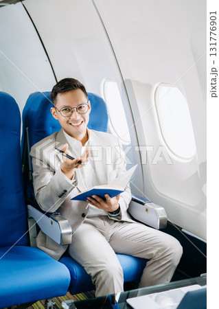 Young Asian executive excels in first class, multitasking with digital tablet, laptop and smartphone. Young Asian executive excels in first class, multitasking with digital tablet, laptop and smartphone. 131776901