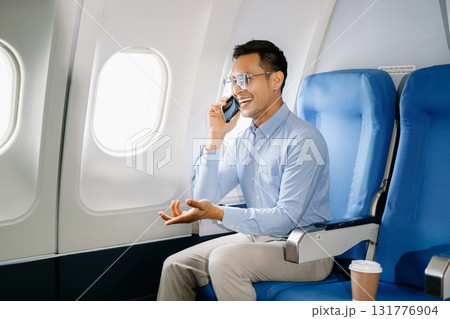 Asian male passenger of airplane sitting in comfortable seat while working laptop and tablet with mock up area using wireless connection. Travel in style, work 131776904