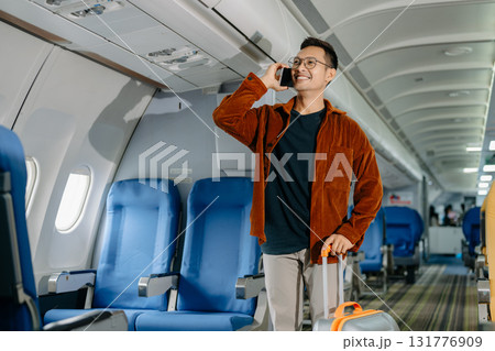 Asian man sitting in a seat in airplane and looking out the window going on a trip vacation travel concept. using a phone, laptop with grace.Capture the allure Asian man sitting in a seat in airplane and looking out the window going on a trip vacation travel concept. using a phone, laptop with grace.Capture the allure 131776909