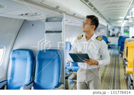 Asian Confident male pilot in uniform leaning at the passenger seat while standing inside of the airplane flight cockpit during takeoff 131776914