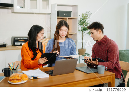 Teamwork and creativity with young adults collaborating on laptops and tablets in a cozy workspace. Teamwork and creativity with young adults collaborating on laptops and tablets in a cozy workspace. 131776999