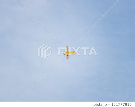 Small ultralight airplane with overhead wing and single propeller flying in sunset sky. 131777916