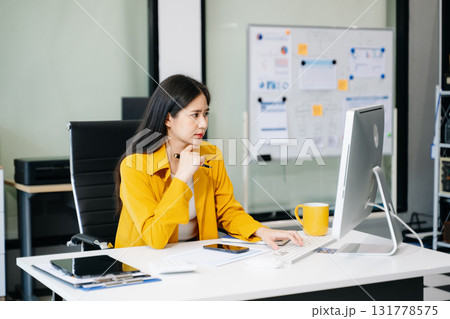 Young Asian businesswoman working with working notepad, tablet and laptop documents talking 131778575