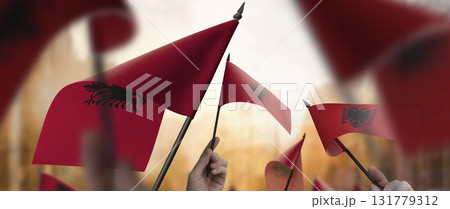 Albania flags in their hands on a blurred urban background 131779312