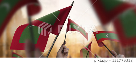 Maldives flags in their hands on a blurred urban background 131779318