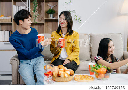 Group of Young Asian friend having, enjoy evening party together at home. Attractive young man and woman having fun, eating food, celebrate at home Group of Young Asian friend having, enjoy evening party together at home. Attractive young man and woman having fun, eating food, celebrate at home 131780138