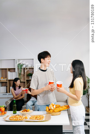 Group of Young Asian friend having, enjoy evening party together at home. Attractive young man and woman having fun, eating food, celebrate at home Group of Young Asian friend having, enjoy evening party together at home. Attractive young man and woman having fun, eating food, celebrate at home 131780189