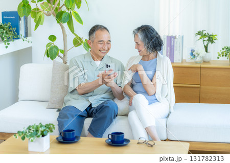 リビングでスマホを見るシニア夫婦 リビングでスマホを見るシニア夫婦 131782313