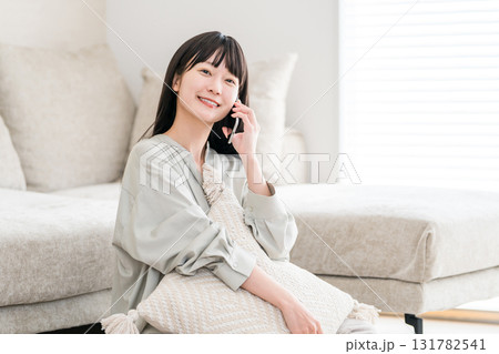 スマホで電話する日本人女性（家,リビング,笑顔） 131782541