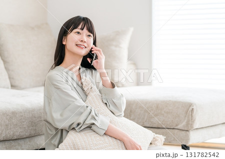 スマホで電話する日本人女性（家,リビング,笑顔） 131782542