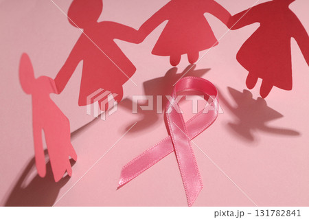 Pink paper figures of girls holding hands with a pink ribbon Pink paper figures of girls holding hands with a pink ribbon 131782841