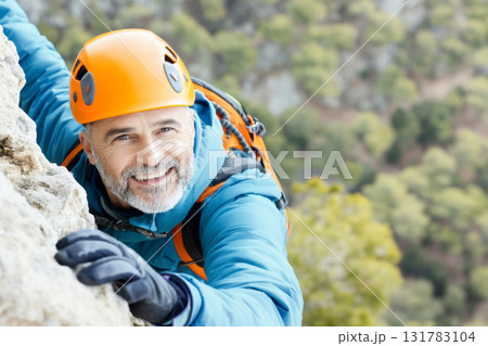 Senior man climbing outdoor rocky cliff in bright gear, adventurous activity 131783104