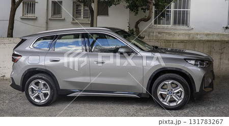 A modern silver BMW with sleek lines, a black roof, and distinctive LED taillights, is parked in a driveway. 131783267