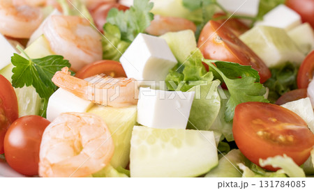 A salad with shrimp, tomatoes, cucumbers, and lettuce 131784085