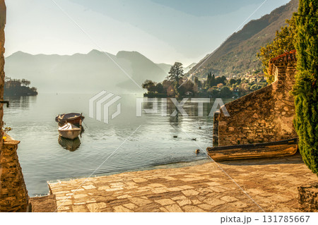 Stone shore for starting on small boats on lake Como.  In distance Colonno town. 131785667