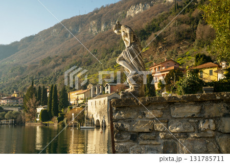 nICE VIEW ONcoastline of  lAKE Como: : villas in distance and old statue for decoration 131785711